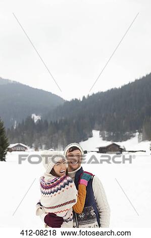 Stock Photo - Portrait of happy couple hugging in snowy field. Fotosearch