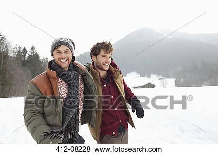 Stock Photo - Portrait of happy men walking in snowy field. Fotosearch