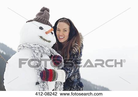 Portrait of happy woman hugging snowman View Large Photo Image Stock Image - Portrait of happy woman hugging snowman. Fotosearch