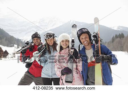Stock Photography - Portrait of smiling friends with skis in snowy field. Fotosearch