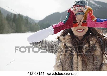 Portrait of smiling woman circling eyes with fingers in snowy field View Large Photo Image Stock Photo - Portrait of smiling woman circling eyes with fingers in snowy field. Fotosearch