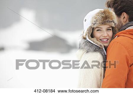 Picture - Portrait of smiling woman hugging man in snowy field. Fotosearch