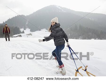 Portrait of smiling woman pulling sled in snowy field View Large Photo Image Stock Photo - Portrait of smiling woman pulling sled in snowy field. Fotosearch