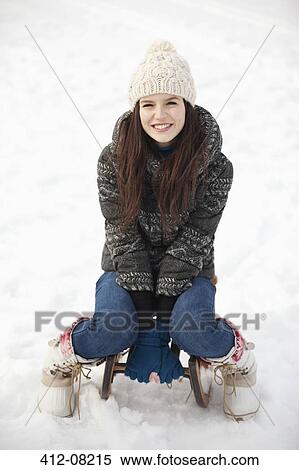 Portrait of smiling woman sitting on sled in snow View Large Photo Image Stock Photography - Portrait of smiling woman sitting on sled in snow. Fotosearch