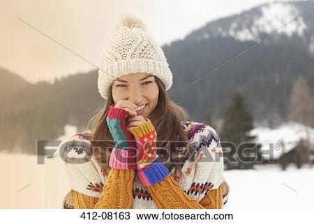 Stock Image - Portrait of smiling woman wearing knit hat in snowy field. Fotosearch