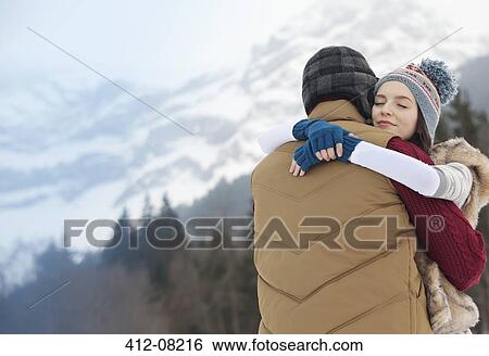 Stock Photograph - Serene couple hugging with mountains in background. Fotosearch