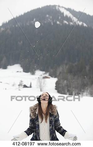Stock Photo - Snowball falling above enthusiastic woman in field. Fotosearch