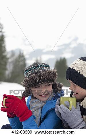 Close up of happy boys drinking hot chocolate in snowy field View Large Photo Image Stock Photo - Close up of happy boys drinking hot chocolate in snowy field. Fotosearch