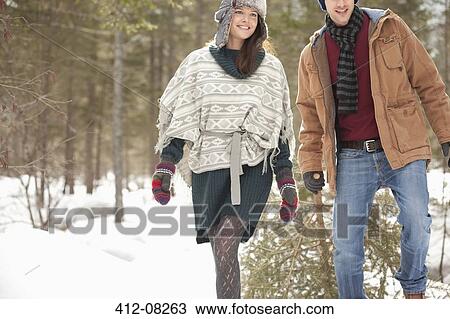 Stock Image - Couple dragging fresh Christmas tree in snowy field. Fotosearch