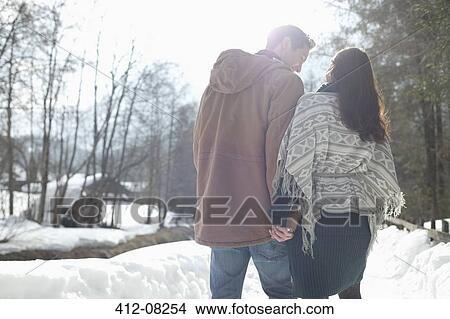 Picture - Couple holding hands and walking in snowy lane. Fotosearch