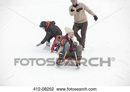Family sledding in snowy field View Large Photo Image Stock Image - Family sledding in snowy field. Fotosearch