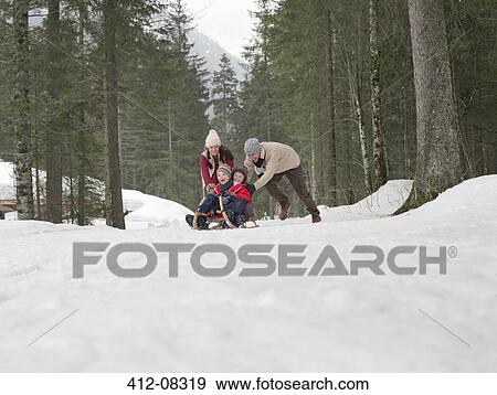 Stock Photo - Family sledding in snowy woods. Fotosearch