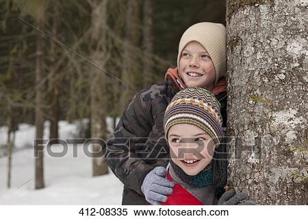 Happy boys leaning against tree trunk in snowy woods View Large Photo Image Stock Photography - Happy boys leaning against tree trunk in snowy woods. Fotosearch
