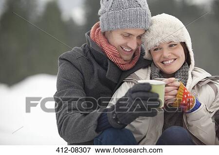 Happy couple drinking coffee in snow View Large Photo Image Stock Photo - Happy couple drinking coffee in snow. Fotosearch