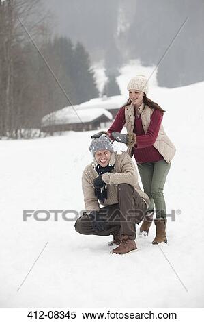 Stock Photography - Happy couple enjoying snowball fight in field. Fotosearch