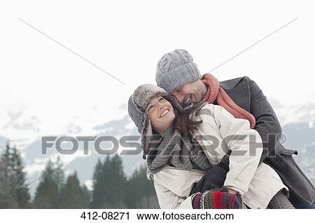 Stock Image - Happy couple hugging with mountains in background. Fotosearch