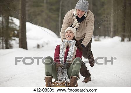 Happy couple sledding in snowy field View Large Photo Image Stock Photography - Happy couple sledding in snowy field. Fotosearch