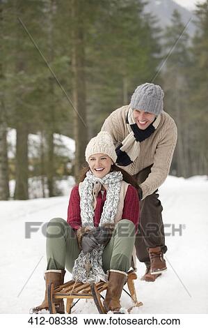 Stock Photo - Happy couple sledding in snowy woods. Fotosearch