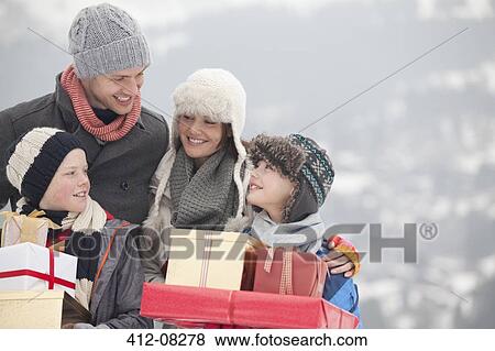 Stock Photo - Happy family carrying Christmas gifts in snow. Fotosearch