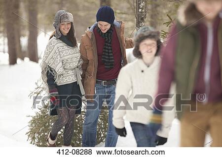 Happy family dragging fresh Christmas tree in snowy woods View Large Photo Image Stock Photo - Happy family dragging fresh Christmas tree in snowy woods. Fotosearch