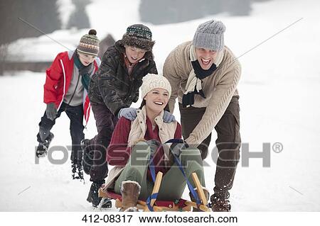 Happy family sledding in snowy field View Large Photo Image Stock Photo - Happy family sledding in snowy field. Fotosearch