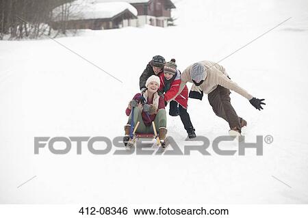 Stock Photograph - Happy family sledding in snowy field. Fotosearch