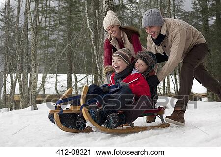 Happy family sledding in snowy woods View Large Photo Image Stock Image - Happy family sledding in snowy woods. Fotosearch