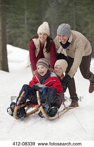 Stock Photo - Happy family sledding in snowy woods. Fotosearch