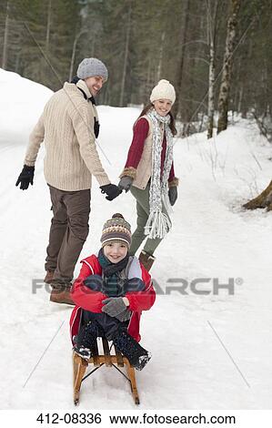 Parents pulling happy boy on sled in snowy woods View Large Photo Image Stock Photograph - Parents pulling happy boy on sled in snowy woods. Fotosearch