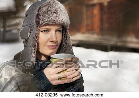 Pensive woman in fur hat drinking coffee outside cabin View Large Photo Image Stock Photography - Pensive woman in fur hat drinking coffee outside cabin. Fotosearch