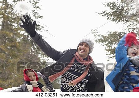 Stock Image - Playful father and sons throwing snow. Fotosearch