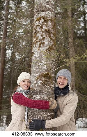 Portrait of happy couple hugging tree trunk in woods View Large Photo Image Stock Image - Portrait of happy couple hugging tree trunk in woods. Fotosearch