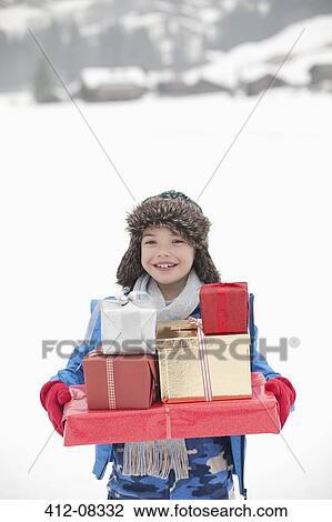 Portrait of smiling boy carrying stack of Christmas gifts in snow View Large Photo Image Stock Image - Portrait of smiling boy carrying stack of Christmas gifts in snow. Fotosearch