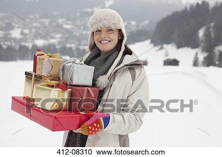 Portrait of smiling woman carrying Christmas gifts in snowy field View Large Photo Image Stock Image - Portrait of smiling woman carrying Christmas gifts in snowy field. Fotosearch