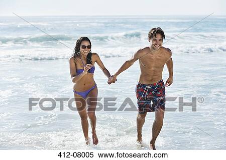 Stock Photography - Couple running in ocean surf. Fotosearch