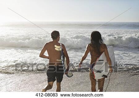 Couple running with surfboards toward ocean View Large Photo Image Stock Image - Couple running with surfboards toward ocean. Fotosearch