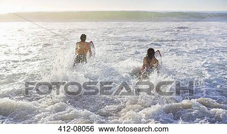 Couple surfing in ocean View Large Photo Image Stock Photograph - Couple surfing in ocean. Fotosearch