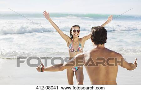 Couple with arms outstretched on beach View Large Photo Image Stock Image - Couple with arms outstretched on beach. Fotosearch