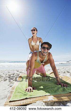 Enthusiastic couple piggybacking on beach View Large Photo Image Stock Image - Enthusiastic couple piggybacking on beach. Fotosearch