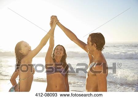 Friends high fiving on beach View Large Photo Image Stock Image - Friends high fiving on beach. Fotosearch