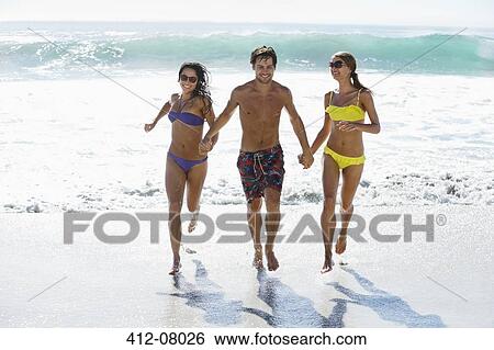 Friends holding hands and running on beach View Large Photo Image Stock Photograph - Friends holding hands and running on beach. Fotosearch