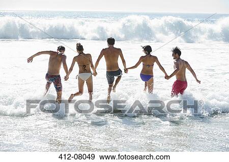 Friends holding hands and splashing in ocean View Large Photo Image Stock Photo - Friends holding hands and splashing in ocean. Fotosearch