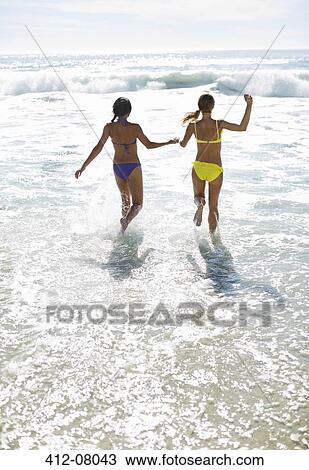Friends in bikinis holding hands and running into ocean View Large Photo Image Stock Image - Friends in bikinis holding hands and running into ocean. Fotosearch