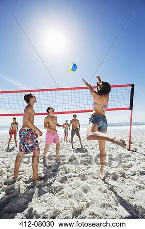 Stock Image - Friends playing beach volleyball. Fotosearch