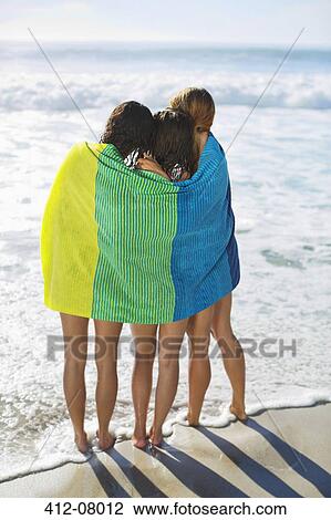 Friends wrapped in towel on beach View Large Photo Image Stock Image - Friends wrapped in towel on beach. Fotosearch