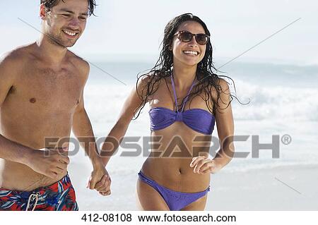 Happy couple holding hands and running on beach View Large Photo Image Stock Photo - Happy couple holding hands and running on beach. Fotosearch