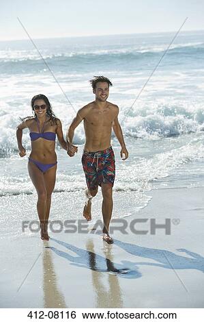 Happy couple holding hands and running on beach View Large Photo Image Stock Photograph - Happy couple holding hands and running on beach. Fotosearch