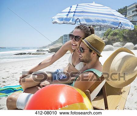Stock Image - Happy couple relaxing on beach. Fotosearch