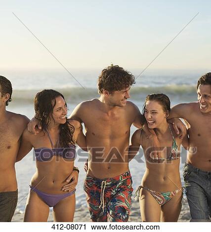 Happy friends in bikinis and swim trunks hugging on beach View Large Photo Image Stock Image - Happy friends in bikinis and swim trunks hugging on beach. Fotosearch