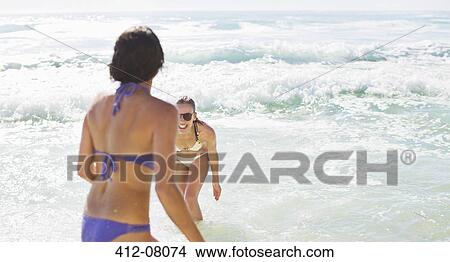 Happy friends in bikinis playing in ocean View Large Photo Image Picture - Happy friends in bikinis playing in ocean. Fotosearch